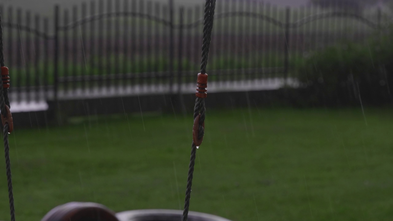 雨中，水从悬挂秋千的绳子上滴下来。视频下载