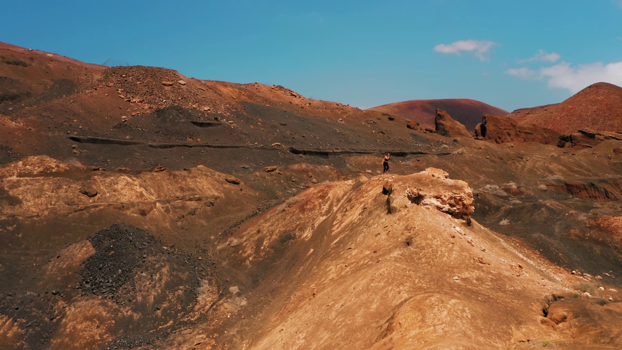 空无一人的红色荒地。火山景观。女孩在山上跑步。旅游目的地。参观火山。徒步旅行的道路。冰冻的熔岩流烧毁了所有生物。人间地狱。视频素材