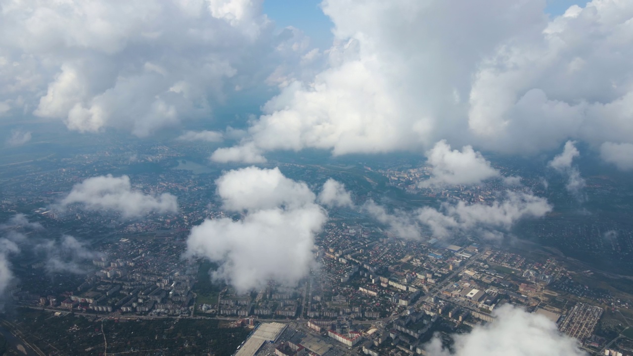 从高空的飞机窗口鸟瞰远处的城市，暴雨前形成的浮肿的积云覆盖着。视频素材