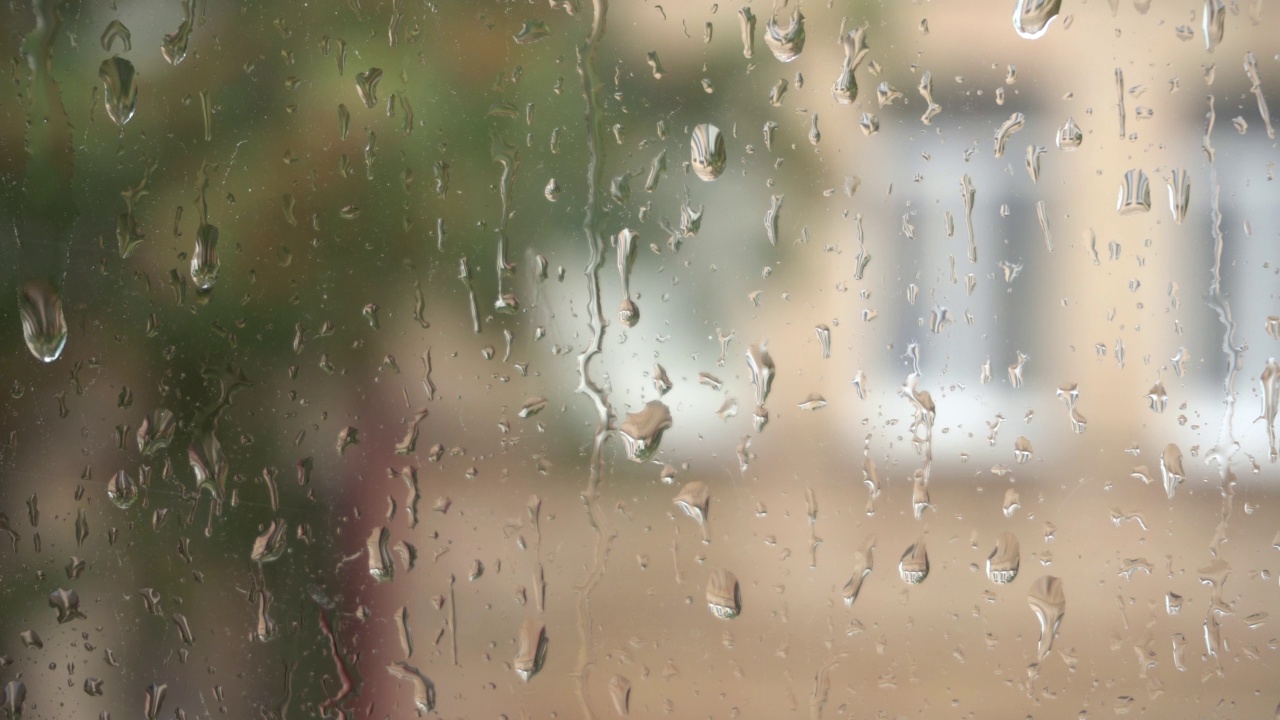 雨点顺着玻璃流下来。雨滴落在窗户上。从窗口。雨天。近距离观察水滴落在玻璃上。视频素材