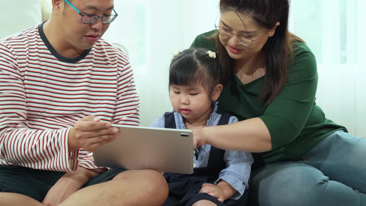 父母使用平板电脑和科技来促进可爱的小女儿的学习。视频素材