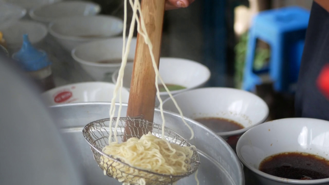 近距离观察一个penjuual mie ayam bakso或肉丸鸡肉面小贩谁正在为买家做鸡肉面。有选择性的重点。视频素材