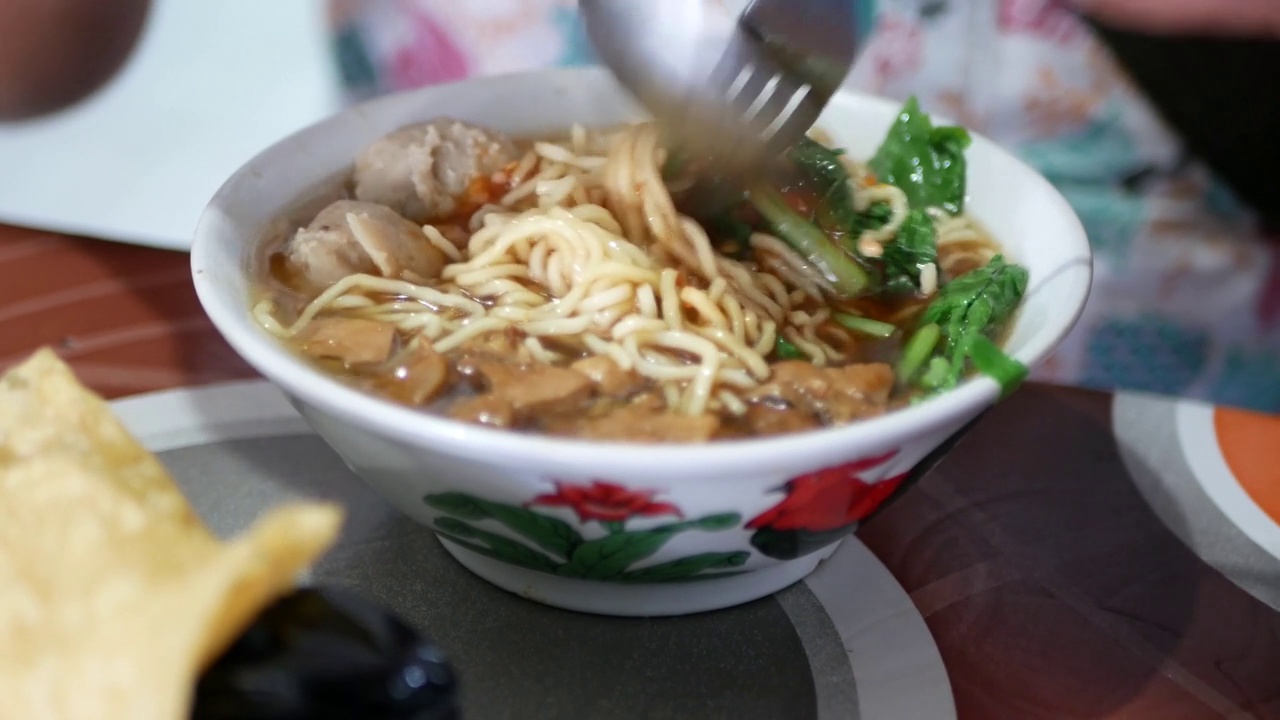 近距离观察一个penjuual mie ayam bakso或肉丸鸡肉面小贩谁正在为买家做鸡肉面。有选择性的重点。视频素材