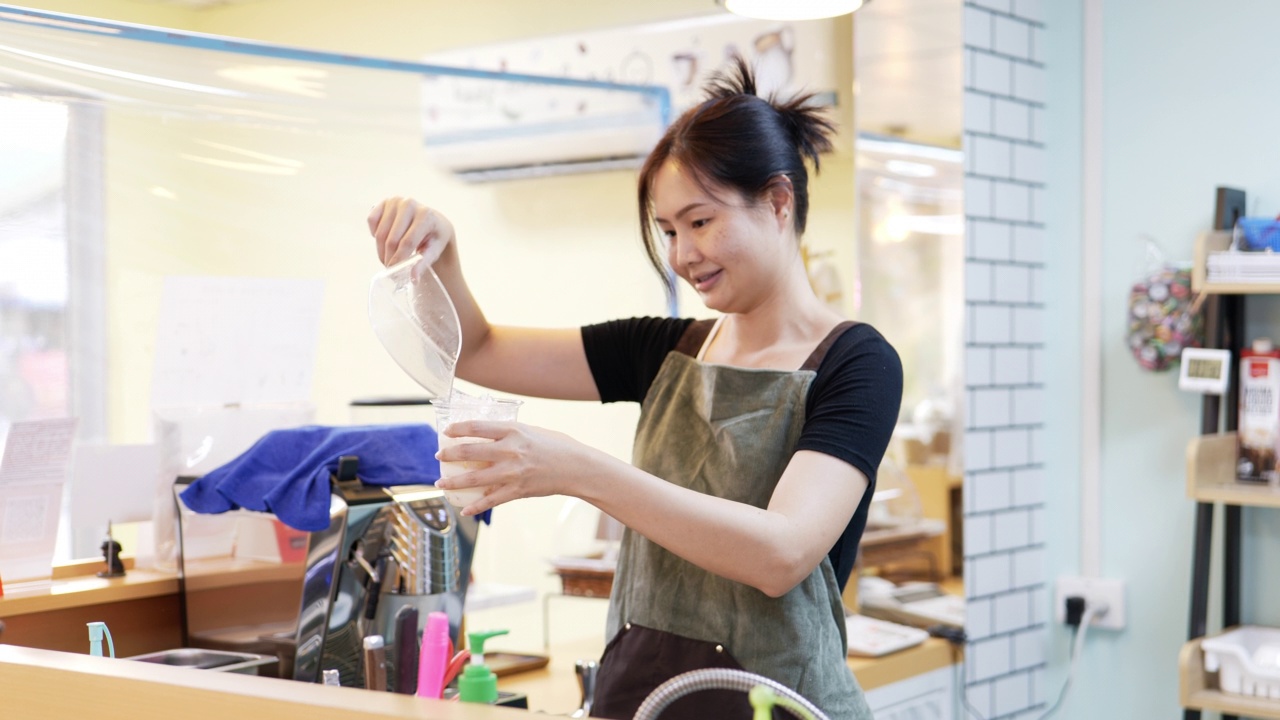 把冰块倒进塑料杯里的年轻女子。视频素材