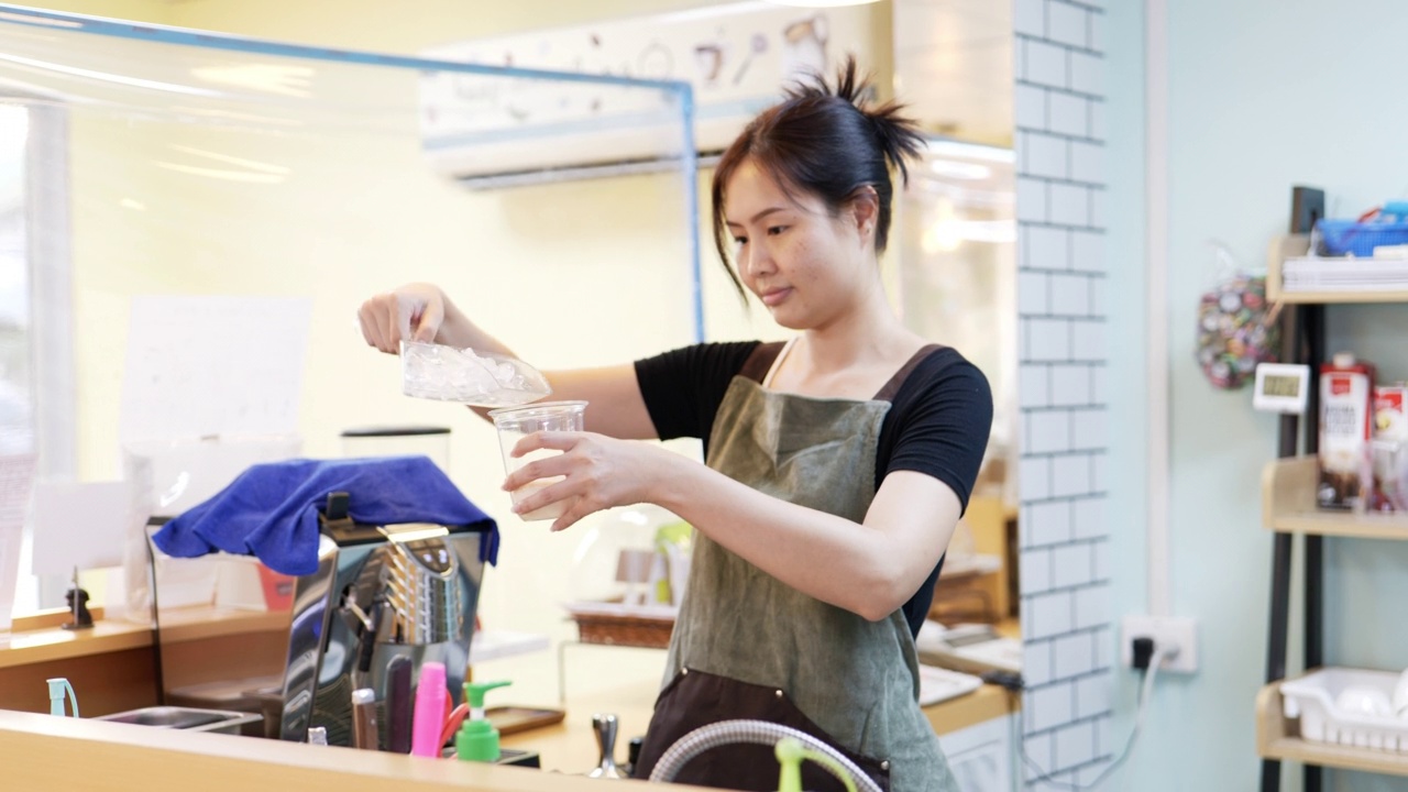 把冰块倒进塑料杯里的年轻女子。视频素材