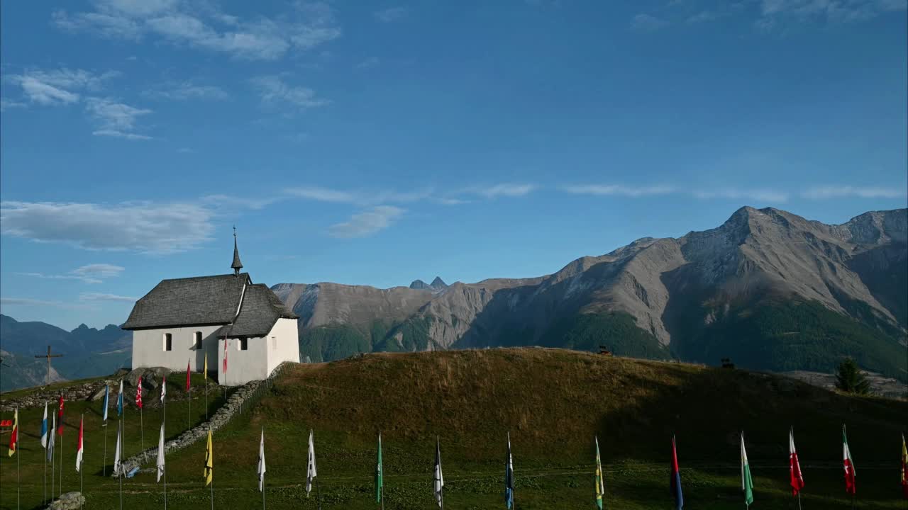 教堂和山脉的风景。实时的教堂与瑞士州旗。Bettmeralp,瑞士。视频素材