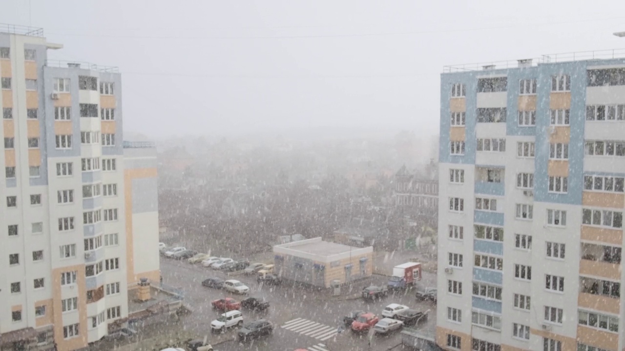 从多层建筑的窗户向城市看冬天下雪的日子。下雪天阴天，人在外面。视频素材