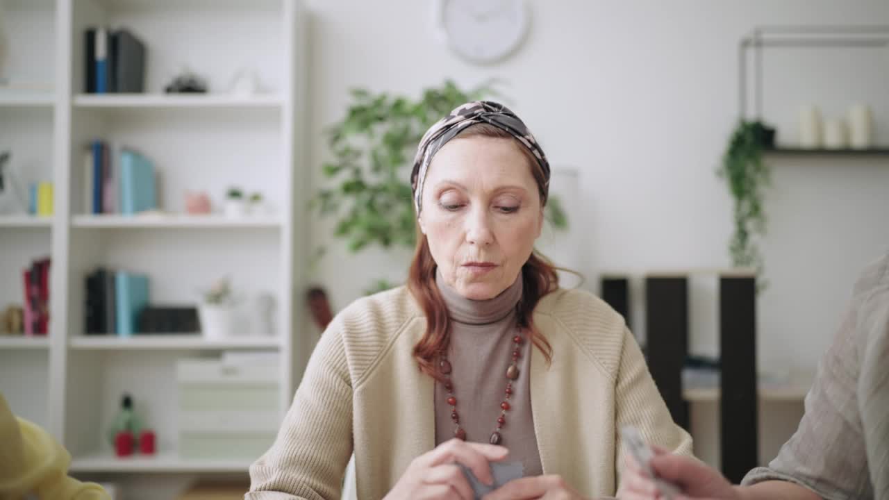 特写严肃的老年妇女打牌扑克，妇女去所有，有趣视频素材