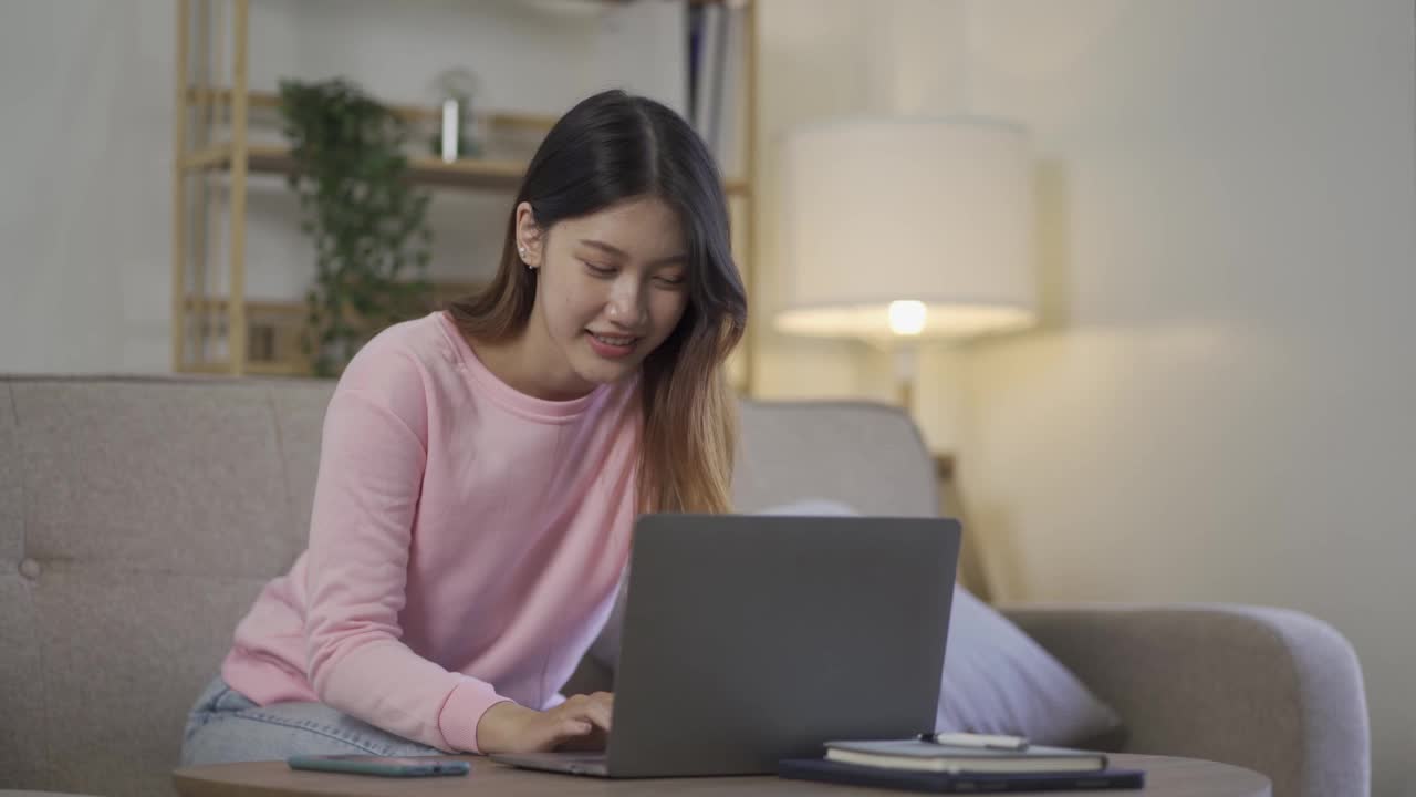 社交媒体，网络和亚洲妇女玩笔记本电脑在家里的沙发互联网女孩玩网上购物游戏视频素材