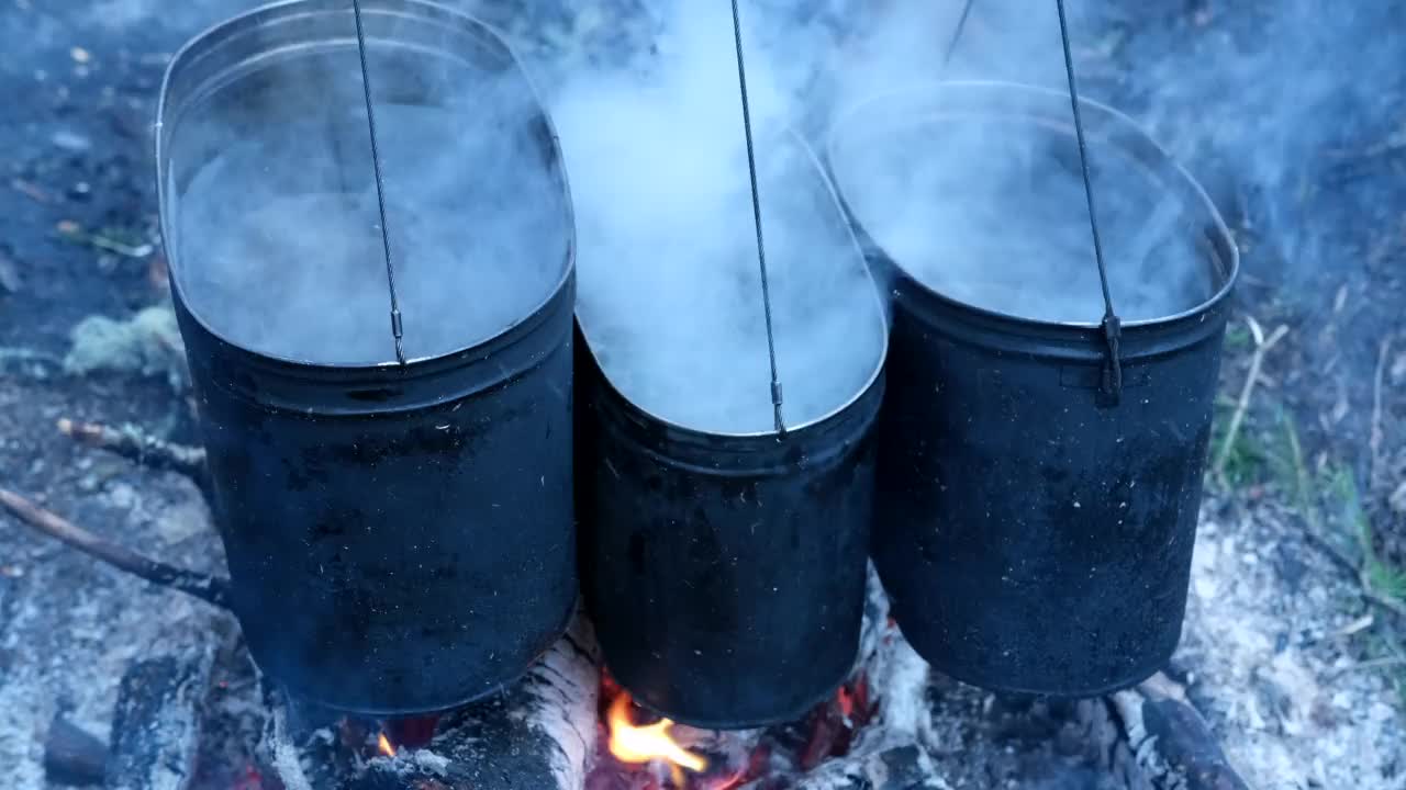 水在3个锅中煮沸，挂在火上与沸水准备晚餐视频素材