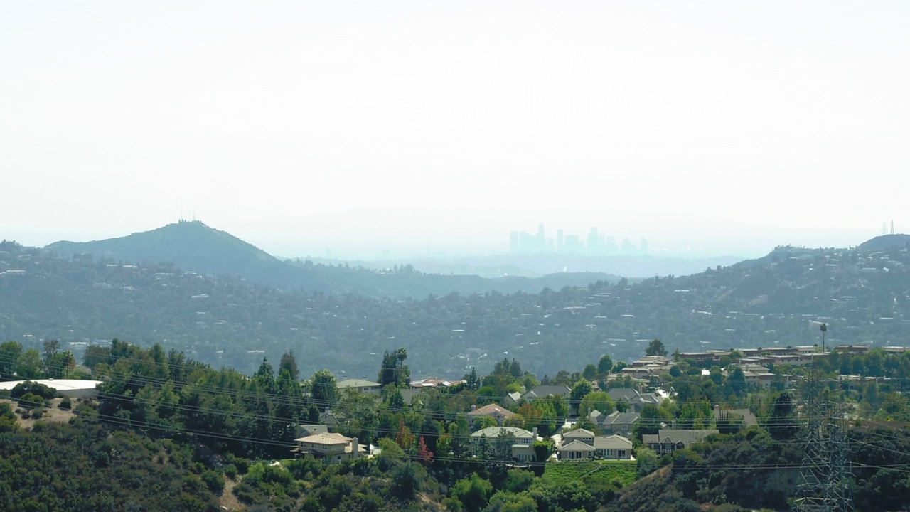 空中向前拍摄的住宅在山上的树木中，无人机在城市的阳光天向前飞行-洛杉矶，加利福尼亚州视频素材