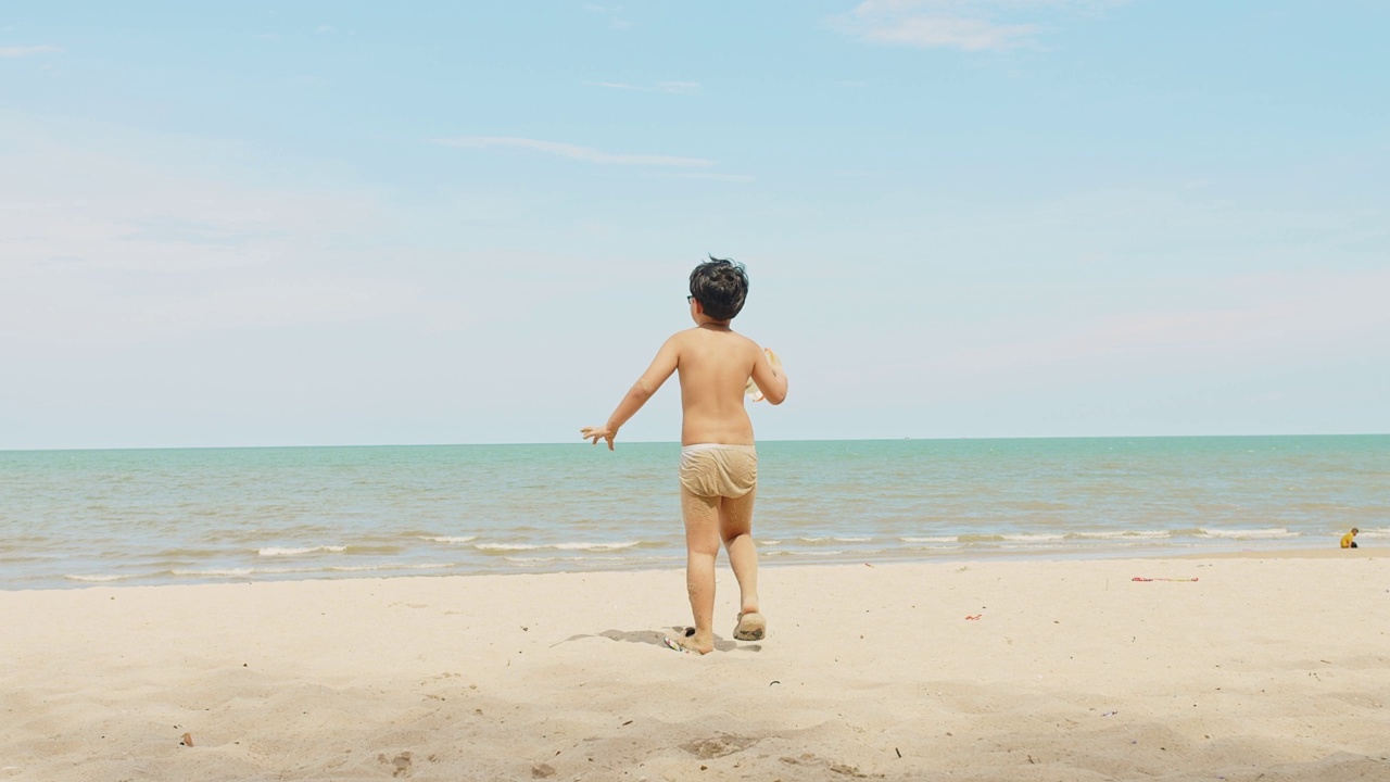 活跃快乐可爱的亚洲儿童男孩享受休闲暑假假期旅行走在热带海洋海滩和玩沙在阳光灿烂的日子蓝色的天空背景视频素材