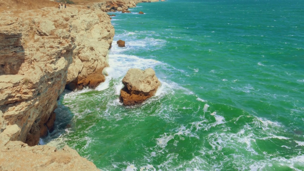 海浪在岩石上荡漾——在刮风的白天，从悬崖顶上看到的海景视频素材