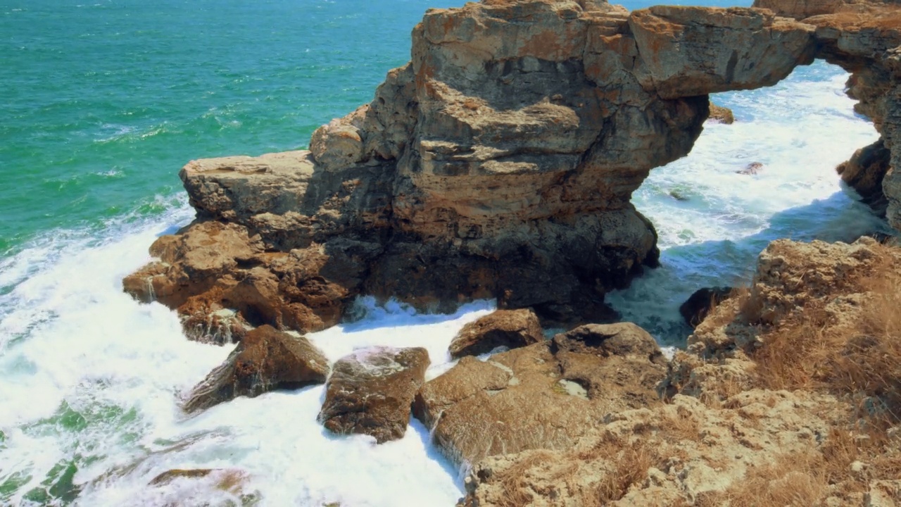 海浪在岩石上荡漾——在刮风的白天，从悬崖顶上看到的海景视频素材