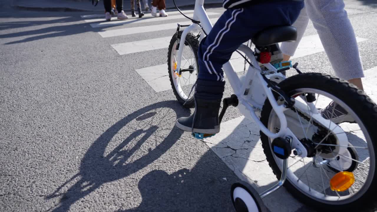 儿童自行车在人行横道上穿过城市街道的特写。孩子在户外穿过城市沥青路的斑马线视频素材