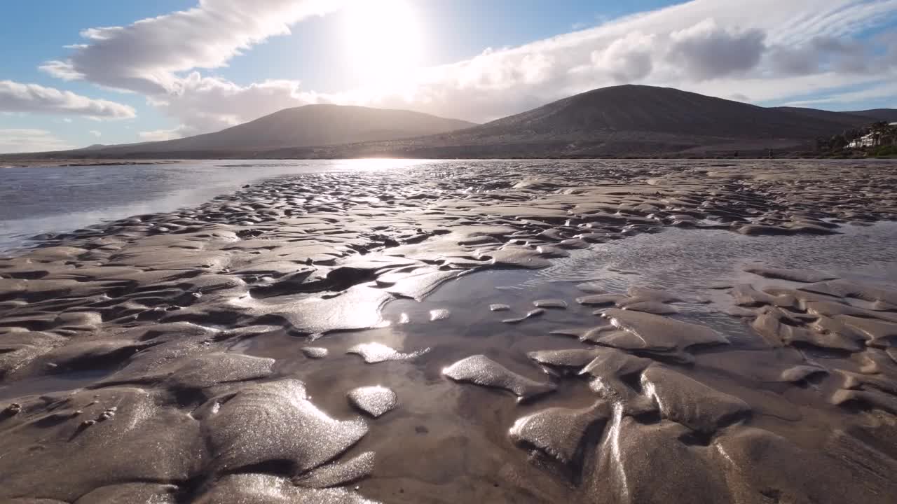 泻湖低潮时的水，波浪痕迹和沙滩，背景是火山视频素材