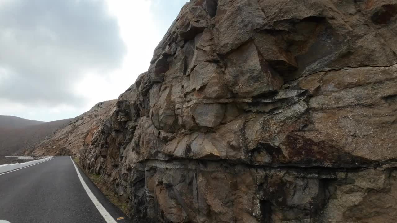 汽车在山路上经过巨大的岩层，火山岩视频素材