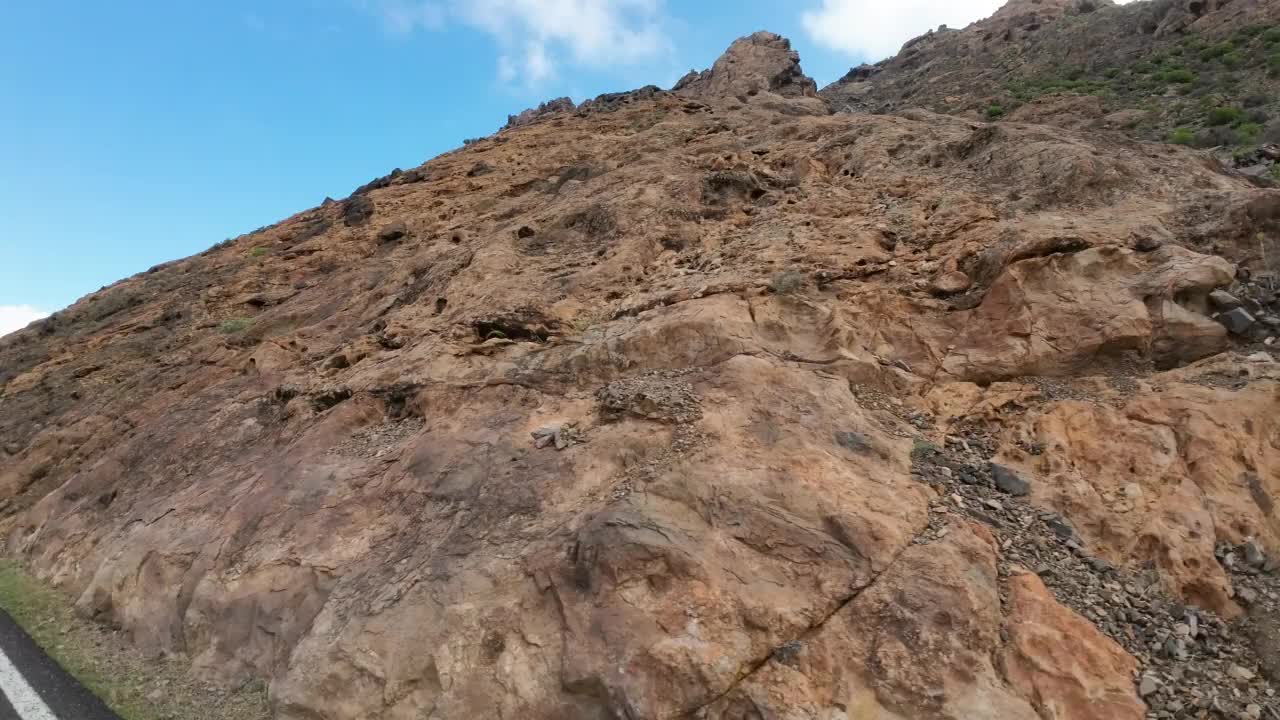 汽车在山路上经过巨大的岩层，火山岩视频素材