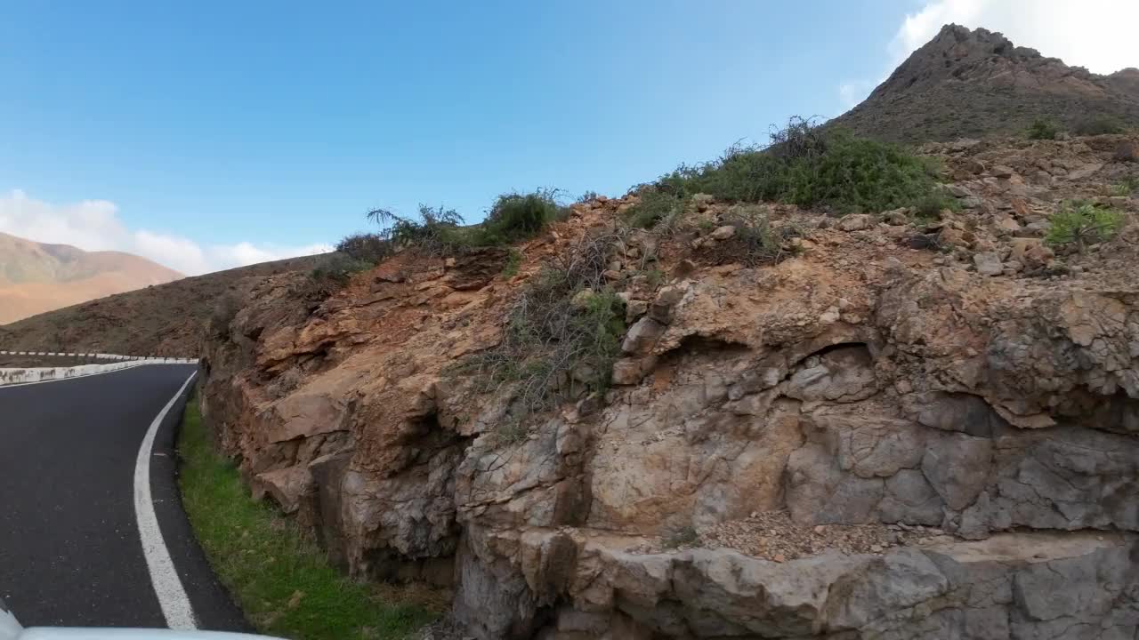 汽车在山路上经过巨大的岩层，火山岩视频素材