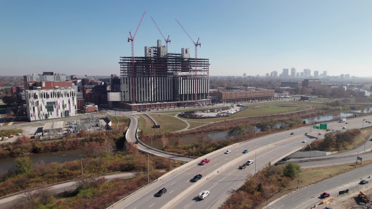 无人机拍摄的建筑工人和起重机在美国中西部城市大学校园附近建造大型结构视频素材