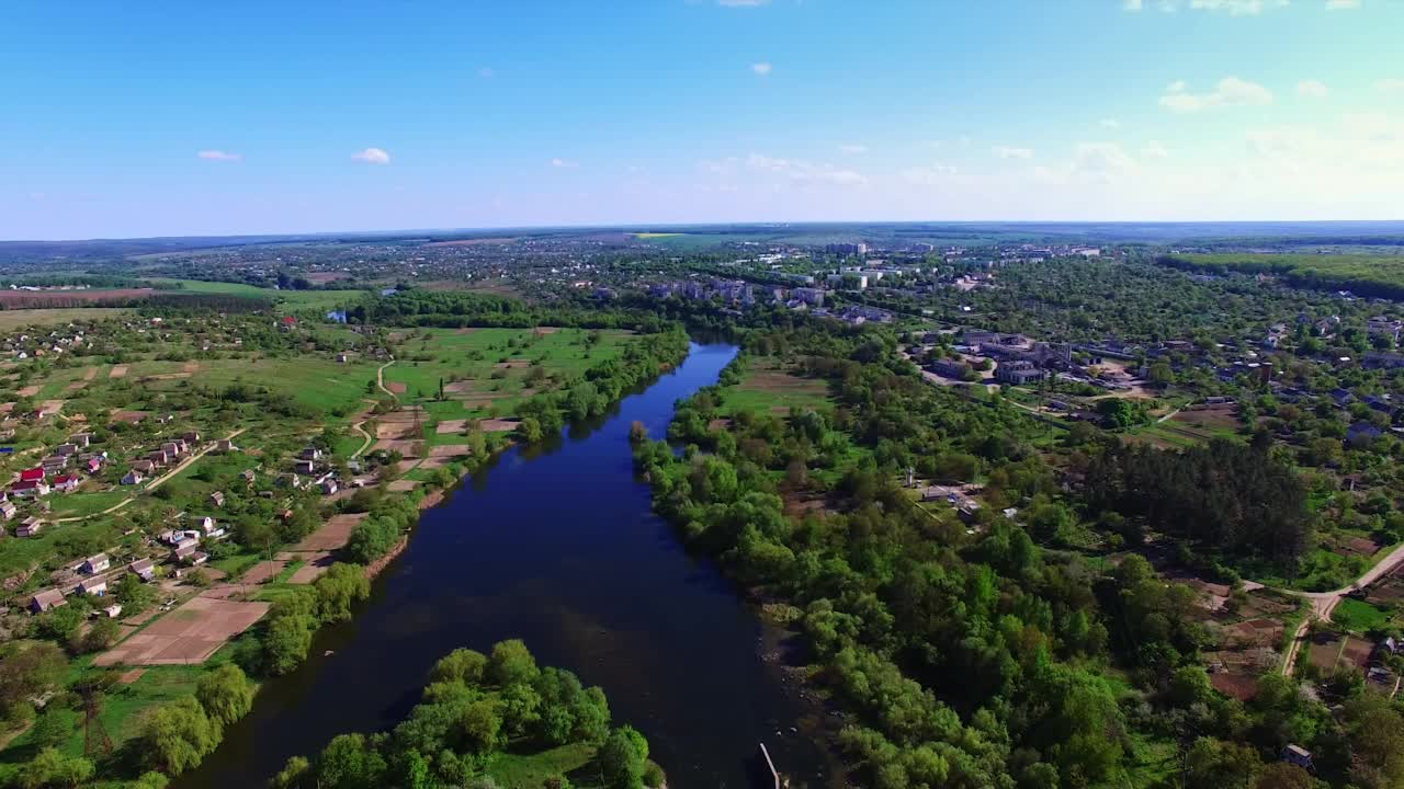 在阳光明媚的夏日里，蓝色的河流流过绿色的城市。从空中看带有水动脉的城市景观。视频素材