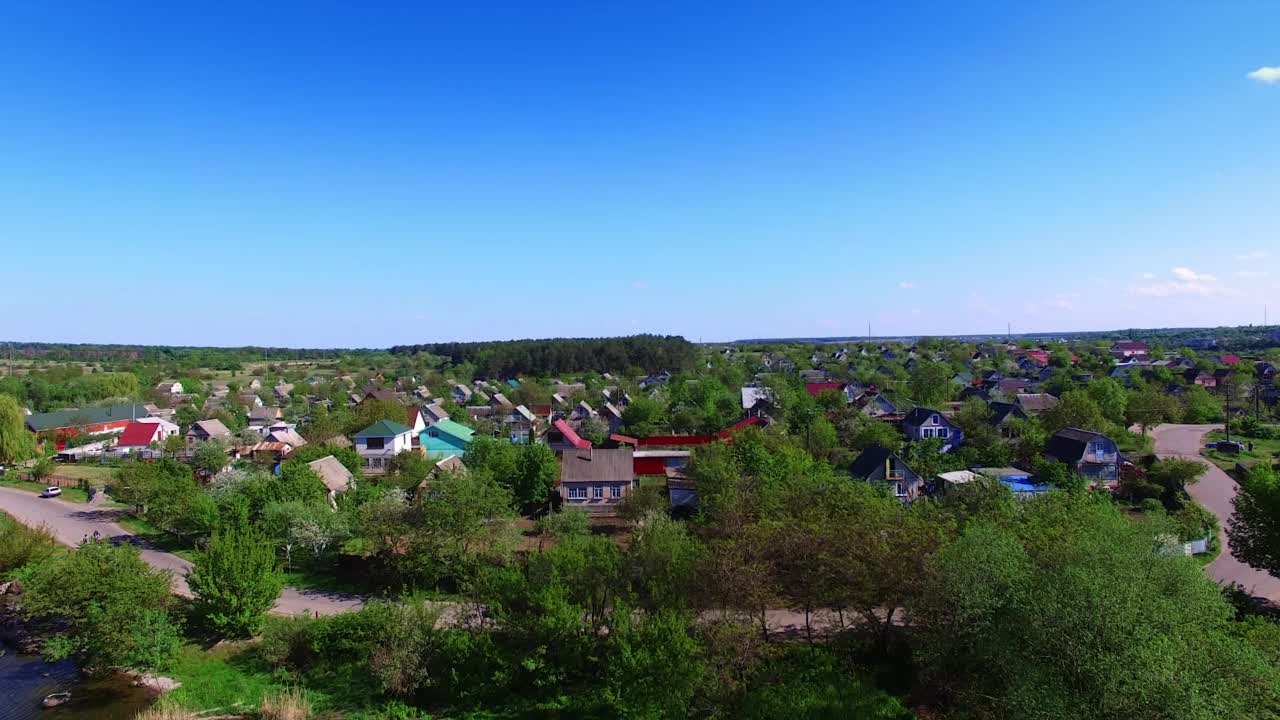 相当大的村庄，绿树丛中有美丽的小屋。阳光明媚的白天，周围有可爱的自然风光的乡村。蓝色晴朗的天空为背景。视频素材