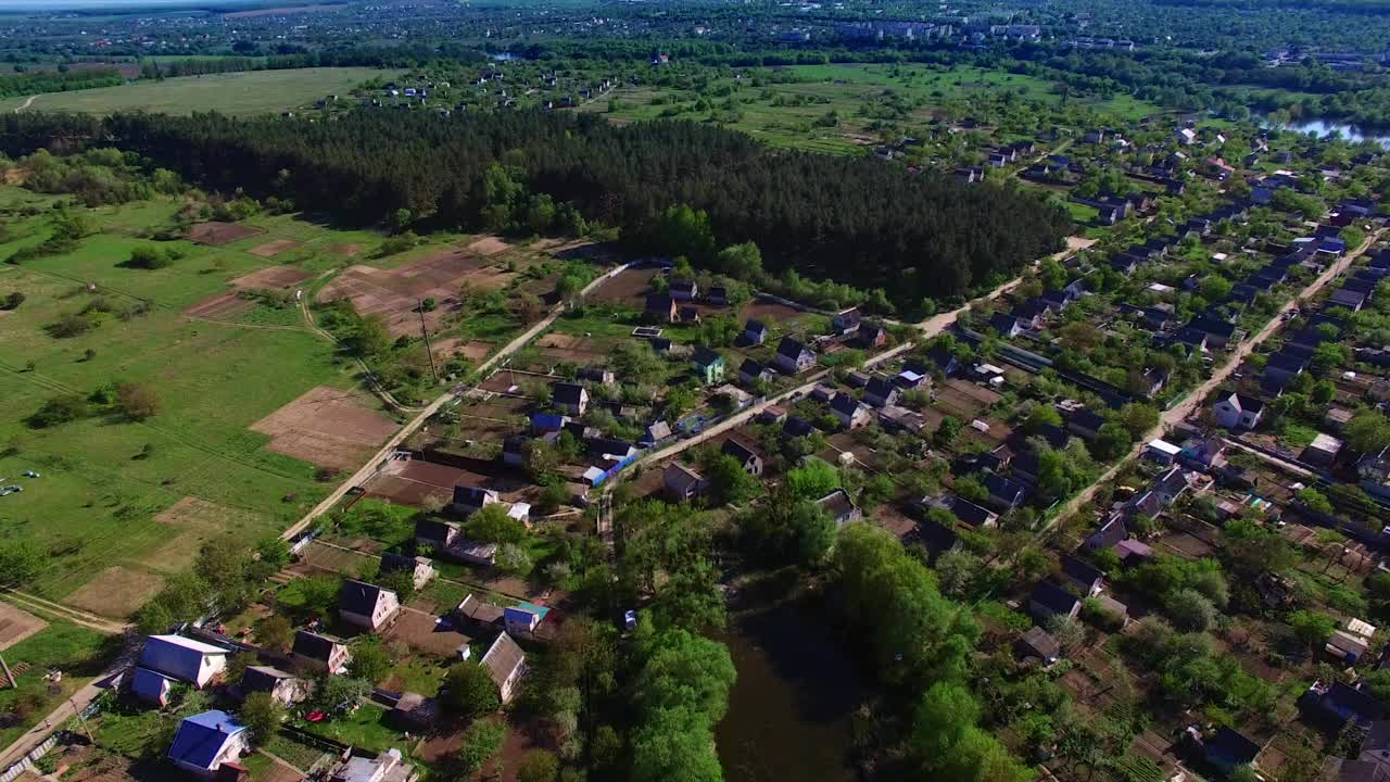 江边美丽的绿色村庄全景。在阳光明媚的日子里，飞过水面。以大城市为背景。视频素材