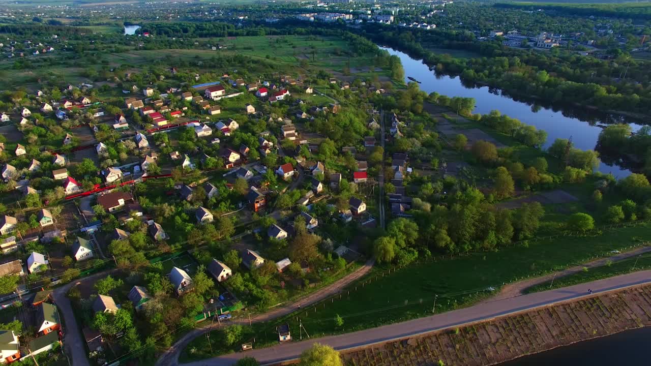 从河岸边的乡村房屋上空飞过。巨大的绿色城市全景背景下的蓝色晴空在黎明。前视图。视频素材