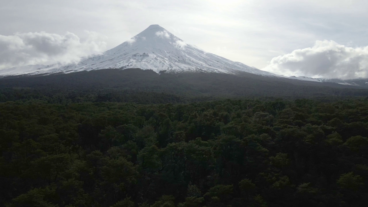 在智利南部的一个多云的日子里，飞机俯瞰奥索尔诺火山，山坡上有一片森林。视频素材