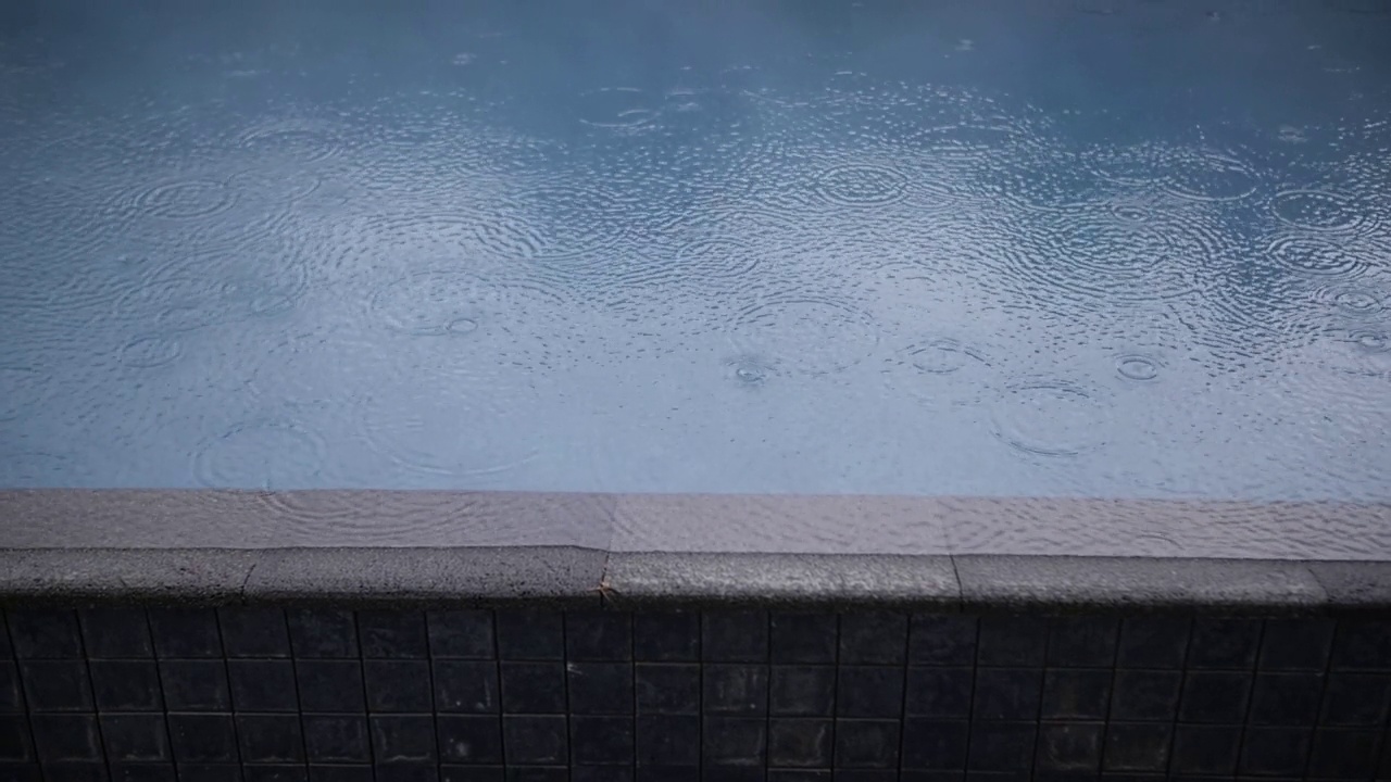 雨滴落在蓝色游泳池的水面上视频素材