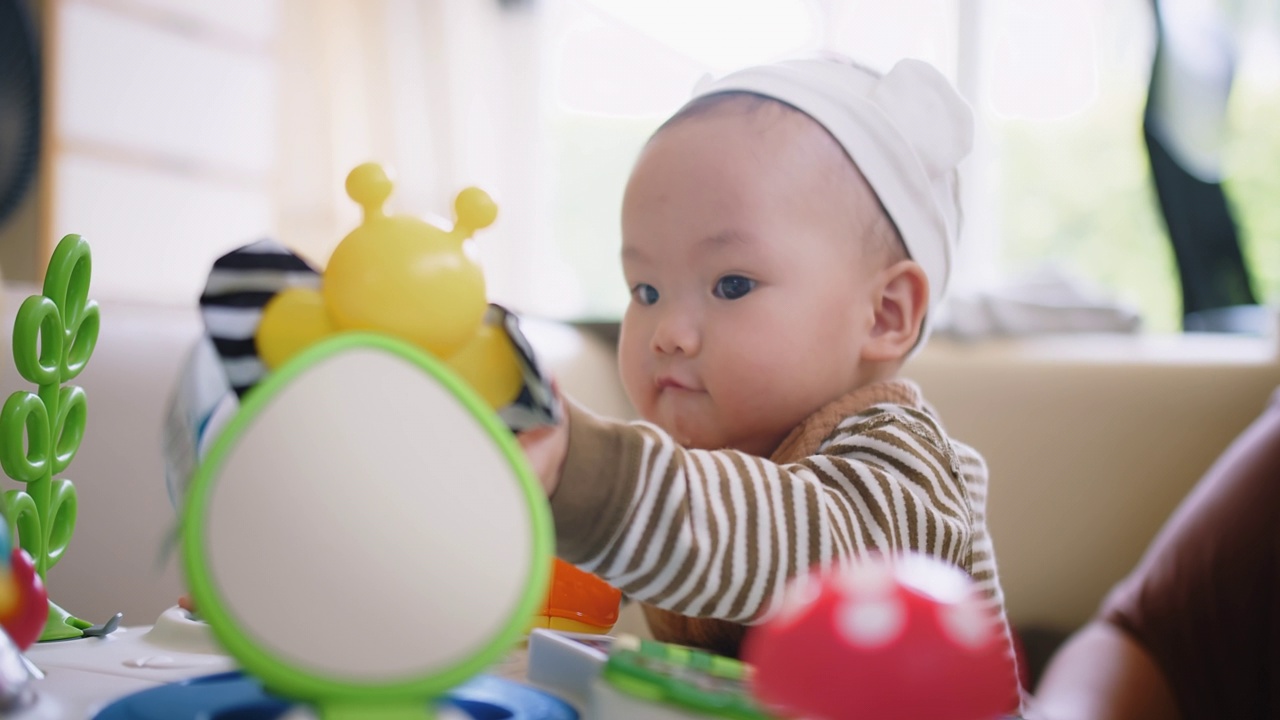 画像可爱的小可爱的亚洲婴儿婴儿幼童坐在客厅玩五颜六色的玩具与乐趣在家里，生活方式学习创造性发展教育儿童的概念视频素材画面1