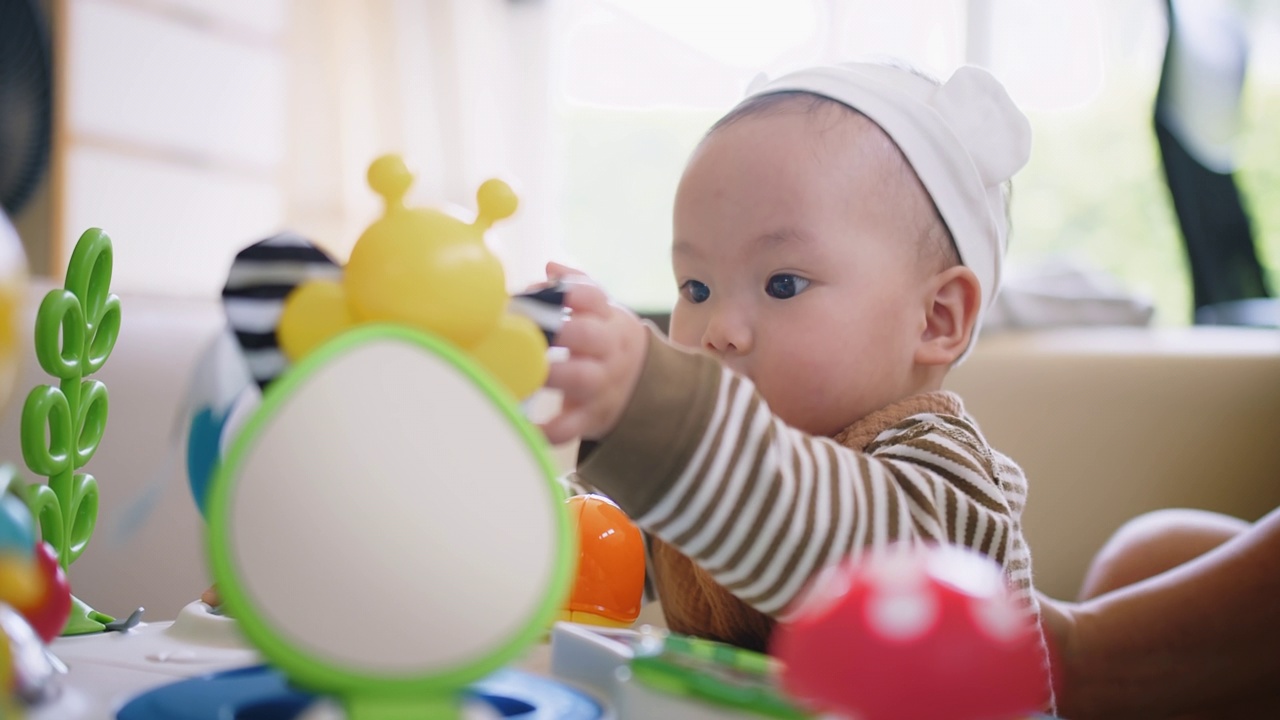 画像可爱的小可爱的亚洲婴儿婴儿幼童坐在客厅玩五颜六色的玩具与乐趣在家里，生活方式学习创造性发展教育儿童的概念视频素材画面2