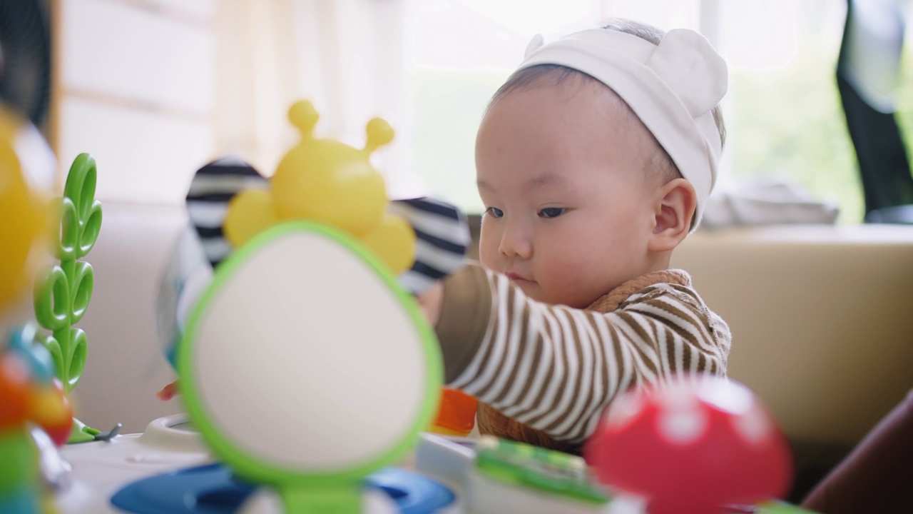 画像可爱的小可爱的亚洲婴儿婴儿幼童坐在客厅玩五颜六色的玩具与乐趣在家里，生活方式学习创造性发展教育儿童的概念视频素材画面4