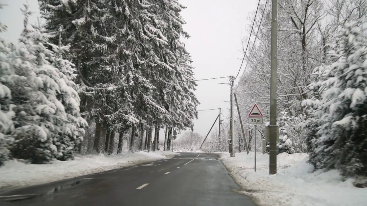 暴风雪后行驶在乡村小路上的汽车。美丽的雪树，屋顶和冬季景观。视频素材