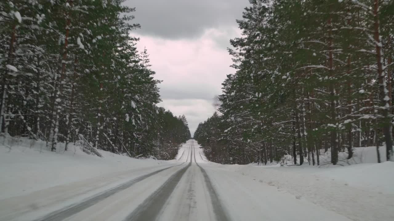 在森林里被雪覆盖的滑溜溜的路上小心驾驶。冬天在空旷的小路上行驶的汽车。视频素材