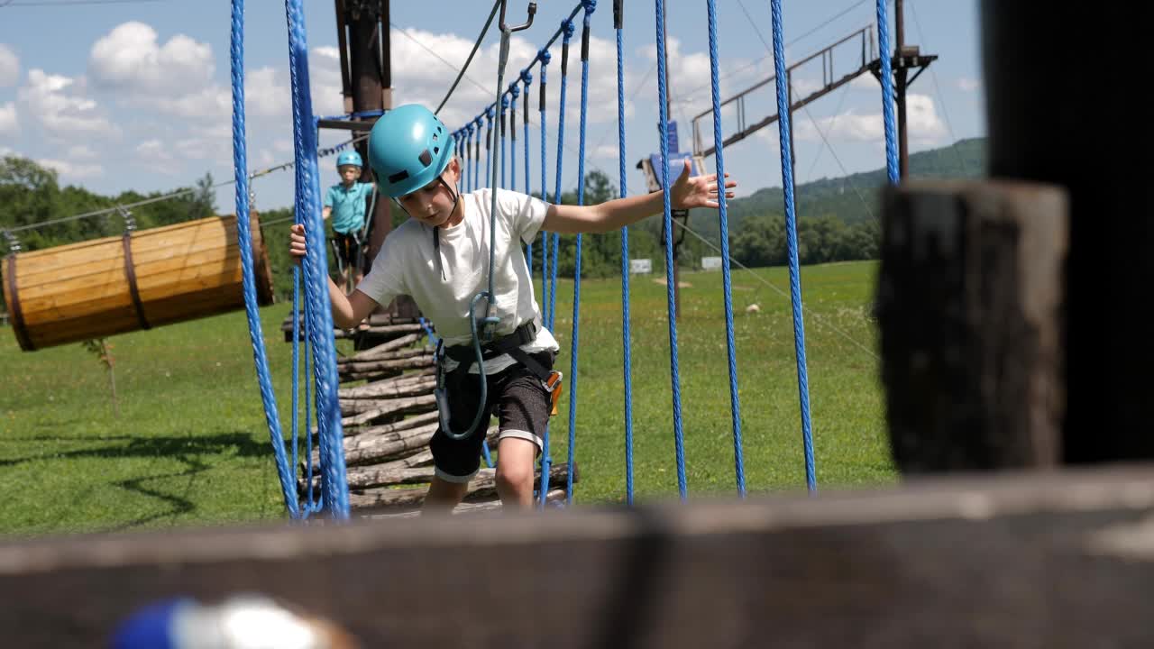 夏天，两个勇敢的男孩在绳索公园里一个接一个地通过障碍。视频素材