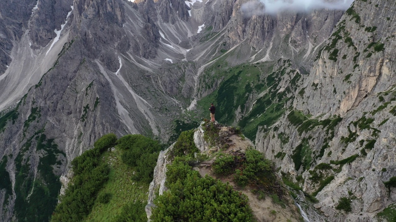 一个人站在一个被落基山脉包围的乡村山顶上的航拍镜头视频素材