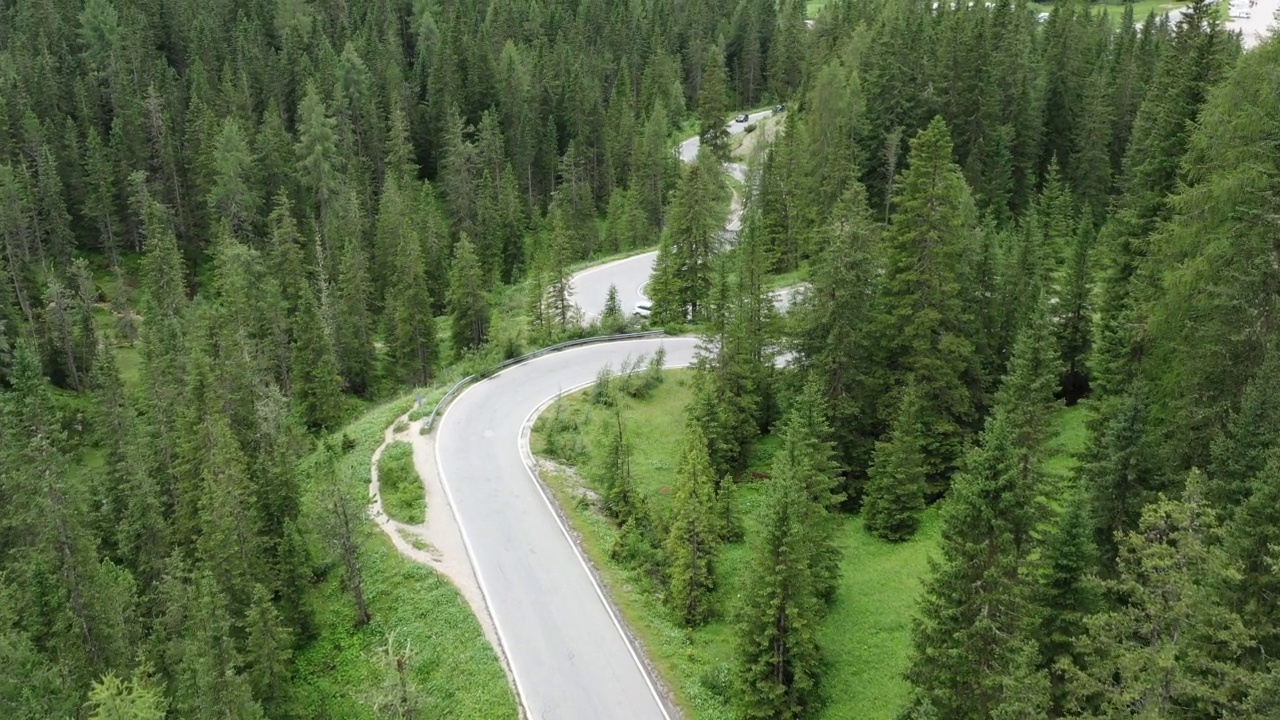 航拍的乡村地区被绿色森林包围的弯曲的柏油路视频素材