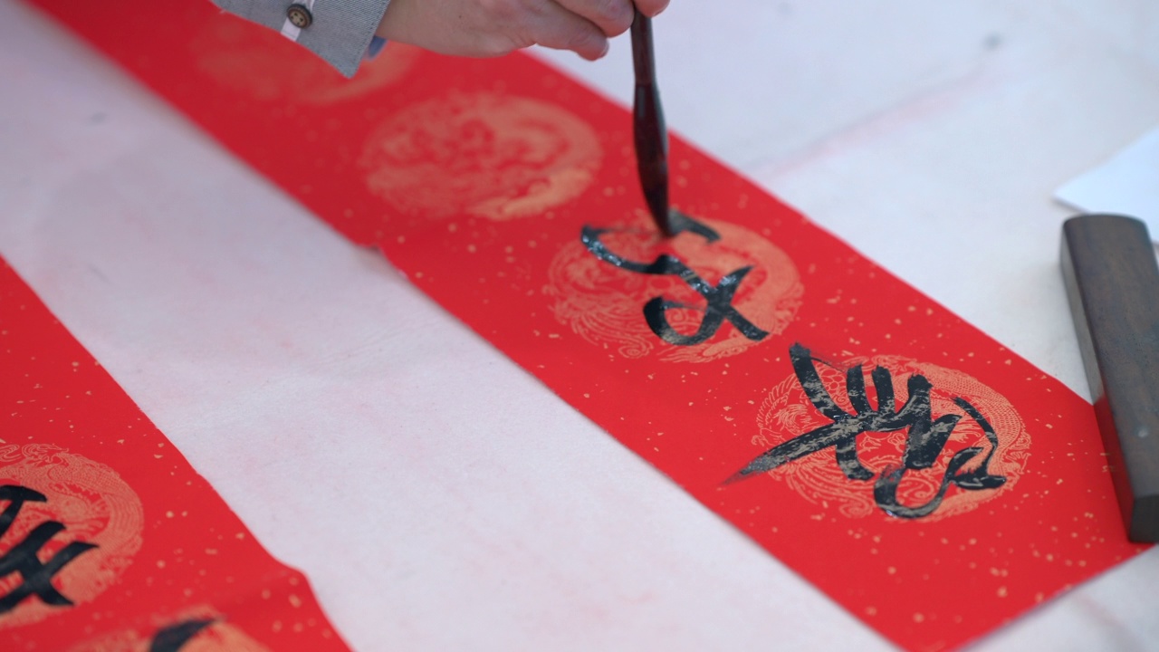 男子在中国农历新年的对联上书写中国传统书法视频素材画面1