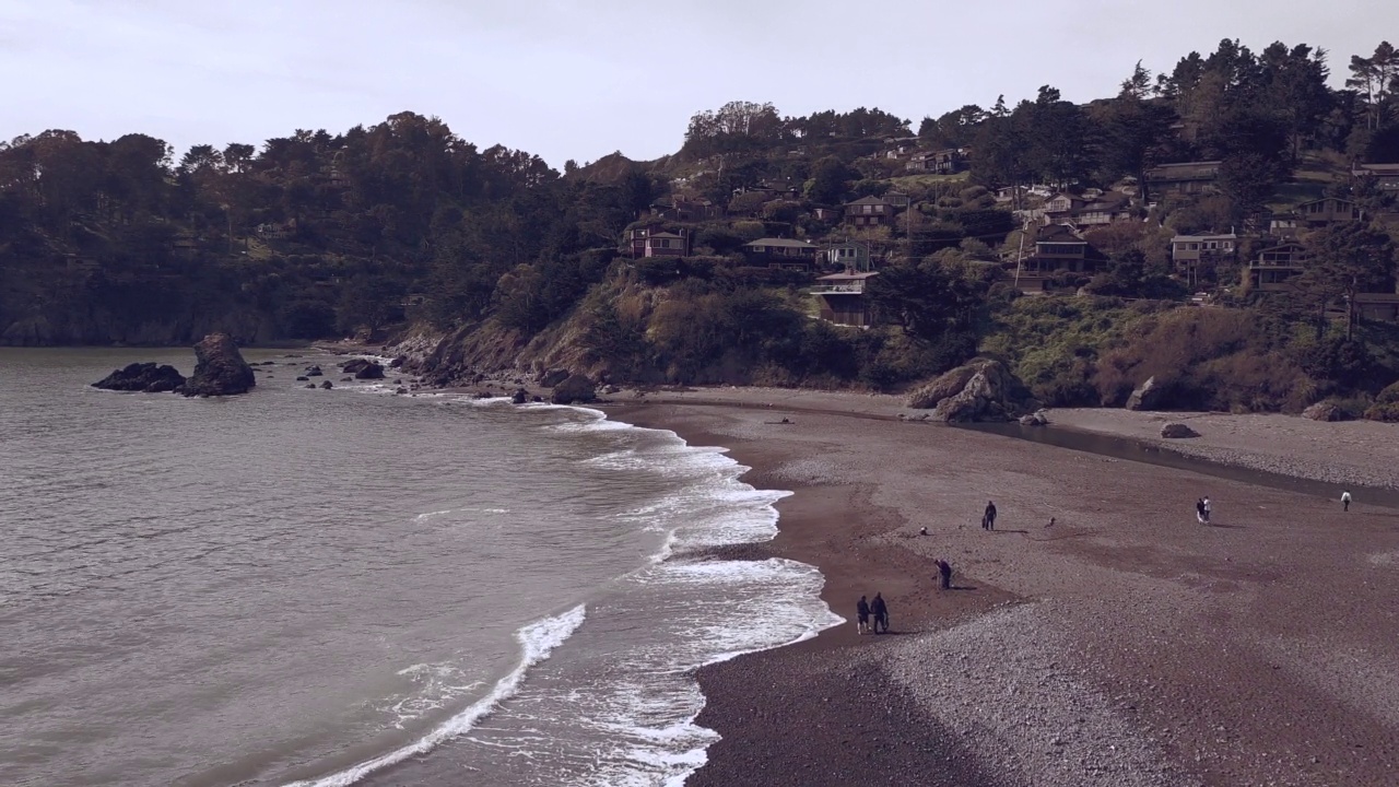 无人机拍摄的海浪撞击沙滩的画面，背景是小山视频素材