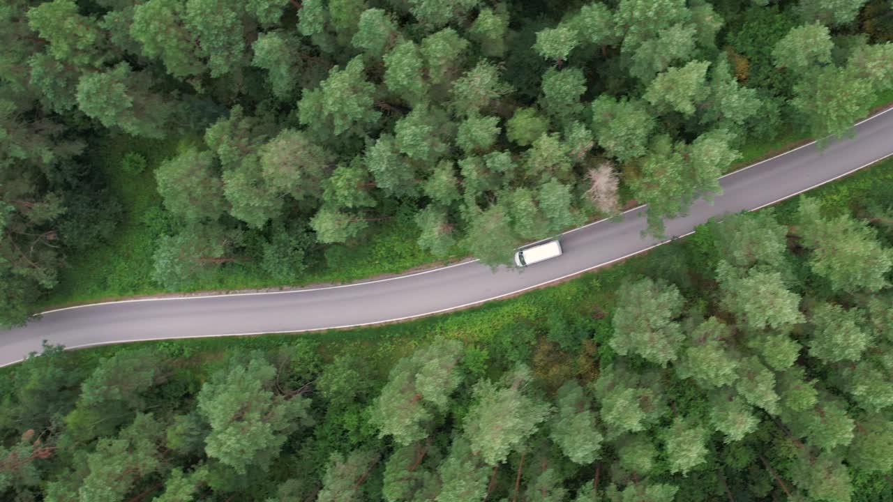 快递运输服务。鸟瞰图白色货车行驶在柏油路穿越广阔的森林在夏天的一天。航拍的汽车行驶在松树林的道路上。风景优美的风景。视频素材