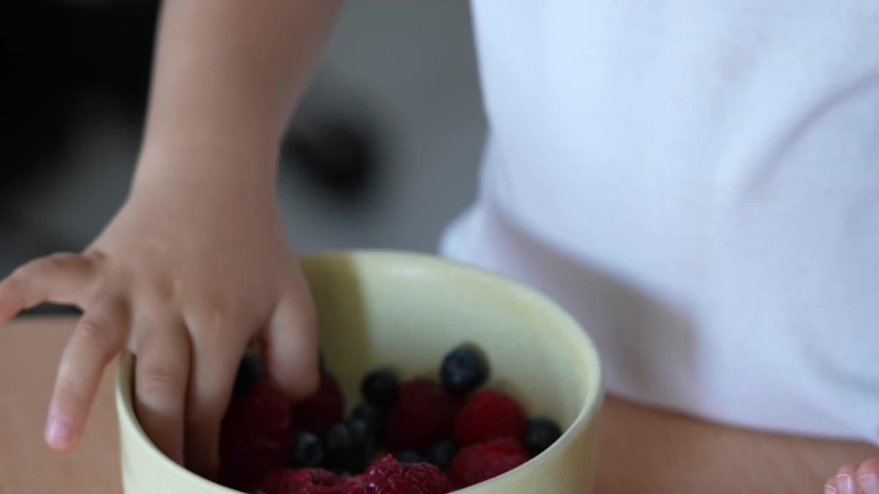 一个小孩用手指吃覆盆子。孩子吃健康零食的画像。有营养的食物视频素材