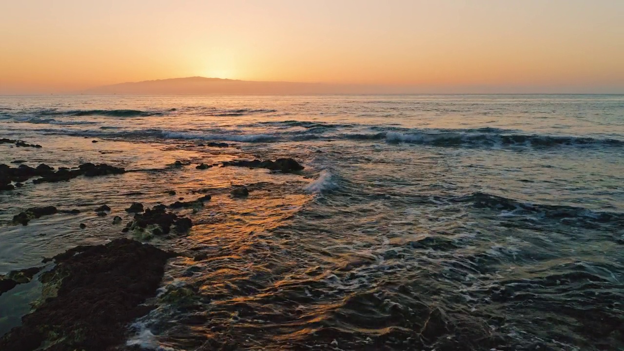 美丽的山岛落日余晖映在海面上，太阳的金色路径映在海水清澈的海面上。景观。天堂的空中电影飞行，越过泡沫的波浪，朝着太阳。视频素材