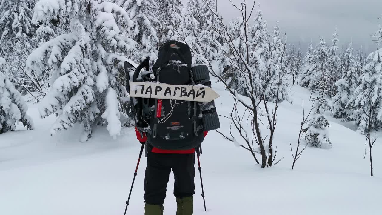 一个背着背包的男人在冬天徒步旅行。他的背包上有个牌子写着巴拉圭视频素材