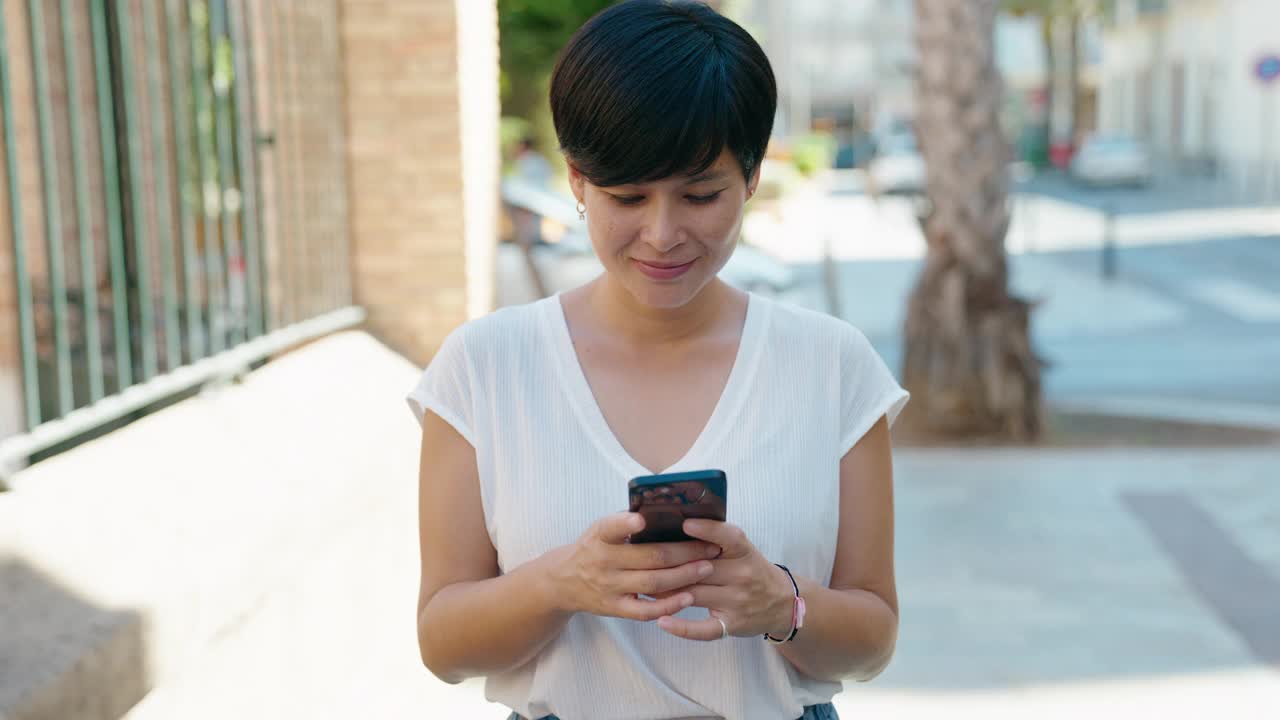 中年中国妇女在街上用智能手机自信地微笑视频素材