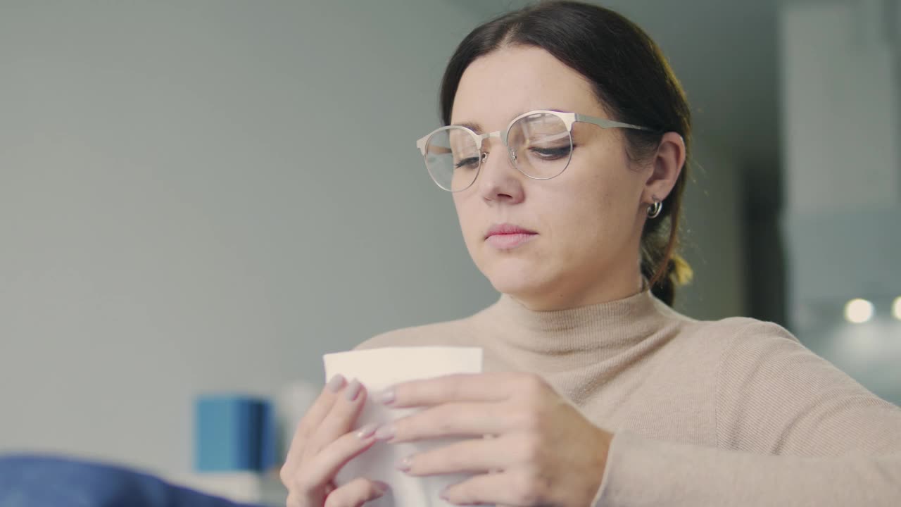 戴眼镜的女人打喷嚏，用餐巾擤鼻涕，季节性感冒视频素材