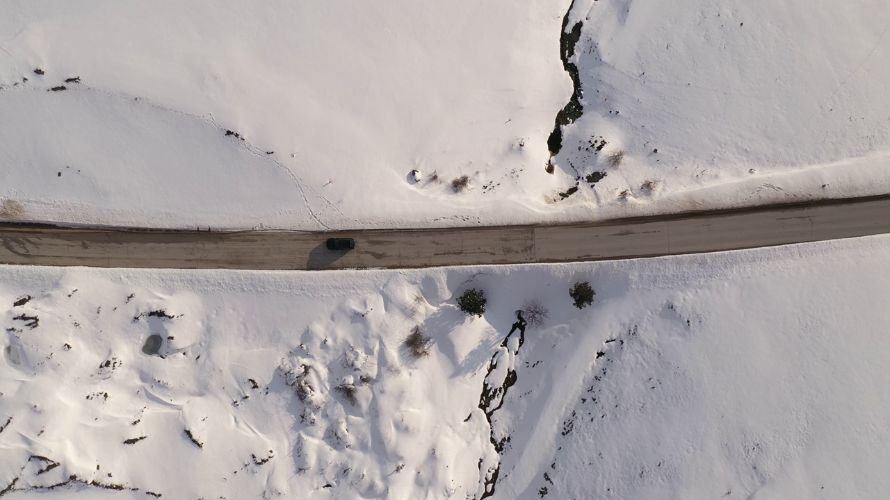 俯视图航拍汽车行驶在冬季被雪包围的道路上，无人机在兹拉蒂博的高速公路上视频素材