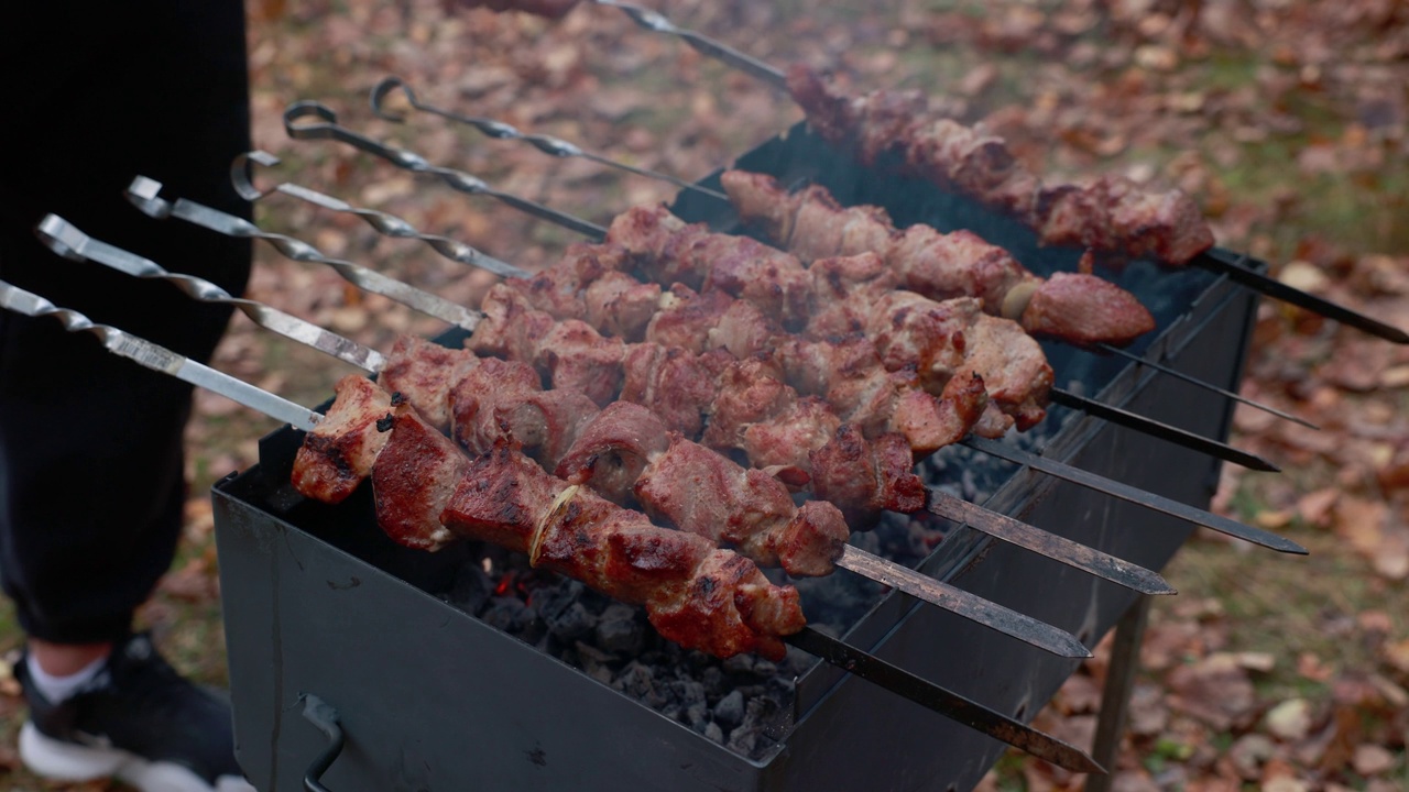 户外烤架上的多汁烧烤。烟熏烤肉。厨师用烤串轮流烤猪肉。4 k。视频素材