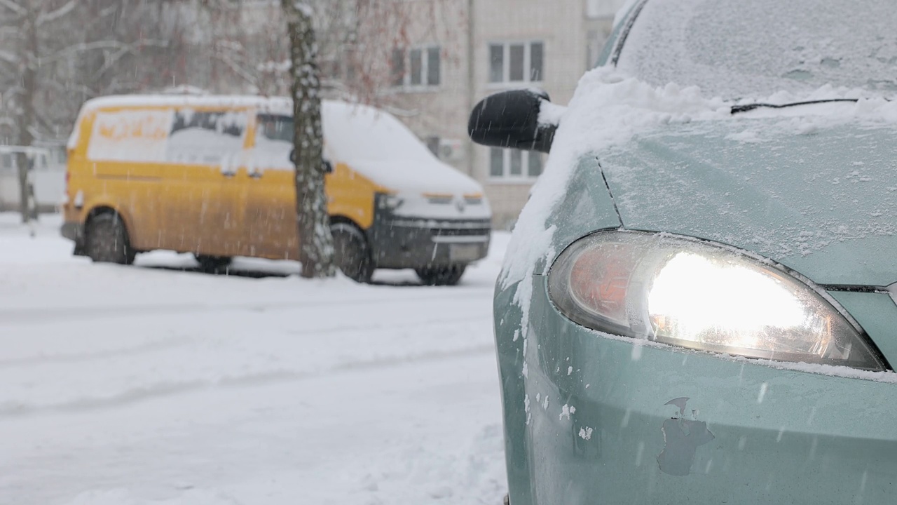 车主清理汽车前灯和引擎盖上的积雪。视频素材