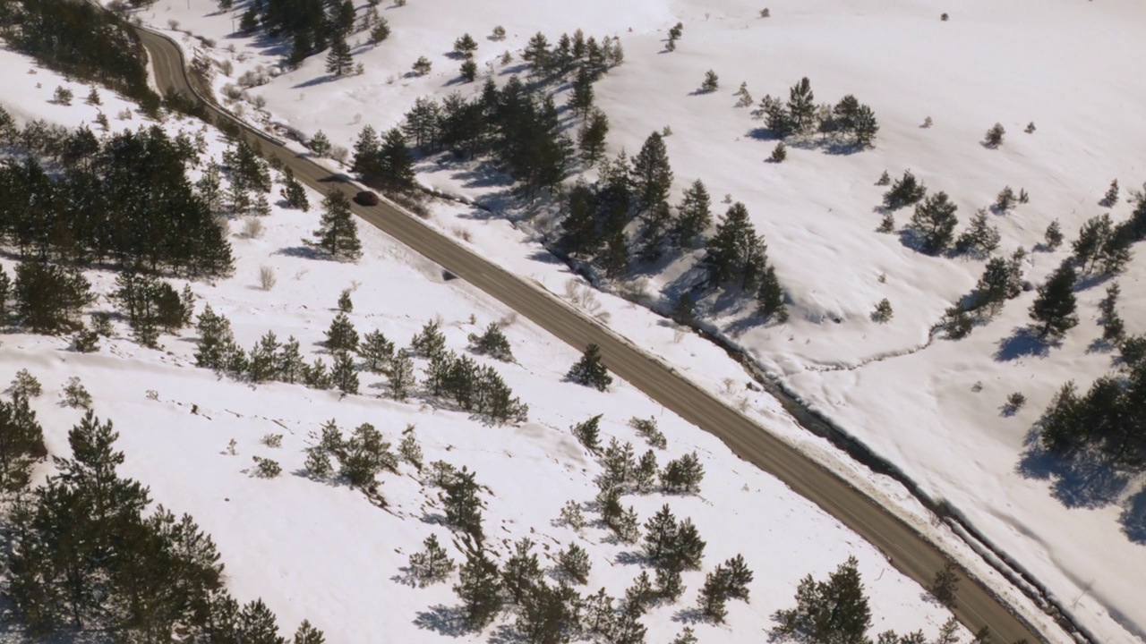 航拍的汽车沿着道路行驶，穿过雪覆盖的景观Zlatibor山在塞尔维亚在冬天视频素材